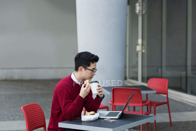 Young man having coffee and breakfast at outdoor cafe — Stock Photo