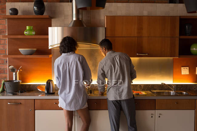 Vue arrière du couple préparant la nourriture ensemble dans la cuisine à la maison — Photo de stock