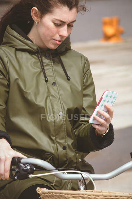 Beautiful woman on bicycle using mobile phone — Stock Photo