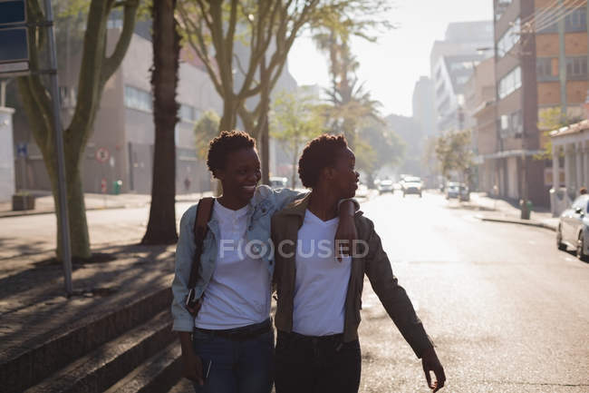 Близнецы прогуливаются по городской улице в солнечный день — стоковое фото