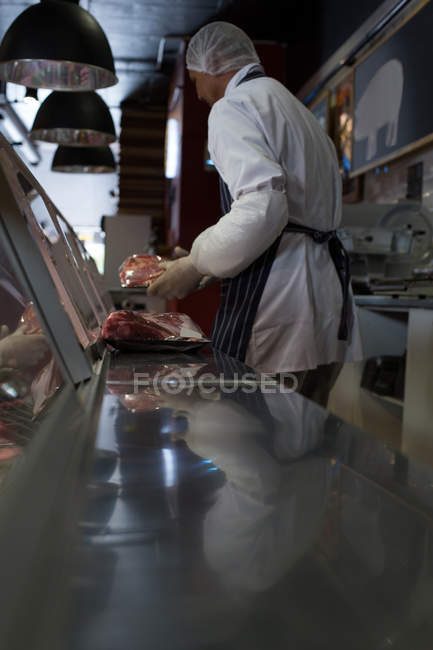 Açougueiro segurando carne no balcão no açougue — Fotografia de Stock