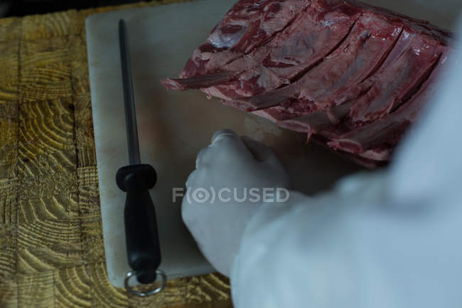 Средняя часть мясника режет мясо в мясной лавке — стоковое фото