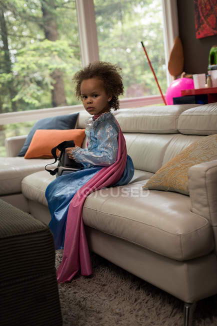 Дівчина з гарнітурою віртуальної реальності сидить на дивані вдома — стокове фото