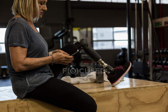 Behinderte ältere Frau benutzt Handy im Fitnessstudio — Stockfoto