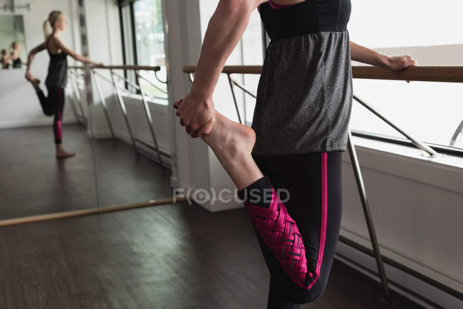 Молода жінка тримає одну ногу, розтягуючись у спортзалі — стокове фото
