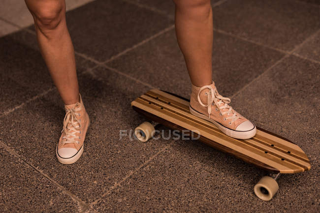 Baixa seção de patinadora feminina em pé no skate — Fotografia de Stock