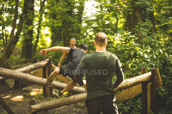 Подходящие мужчины тренируются на полосе препятствий в учебном лагере — стоковое фото