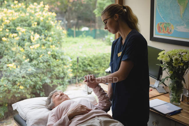 Фізіотерапевт дає масаж рук літній жінці вдома — стокове фото