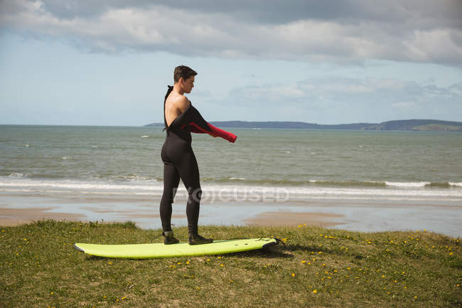 Vista lateral del surfista con tabla de surf preparándose para el surf - foto de stock