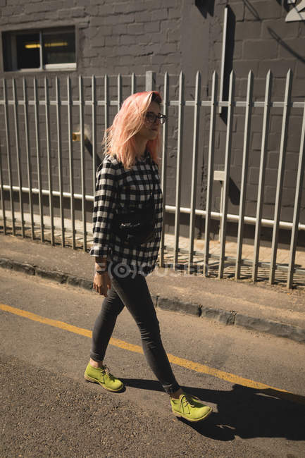 Jovem mulher caminhando em uma estrada durante o dia — Fotografia de Stock