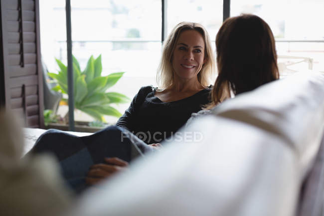 Pareja lesbiana interactuando entre sí en la sala de estar en casa - foto de stock