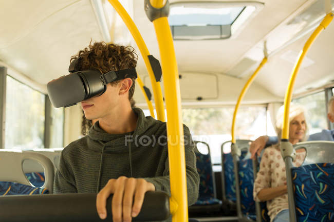 Молодий чоловік використовує гарнітуру віртуальної реальності під час подорожі в автобусі — стокове фото