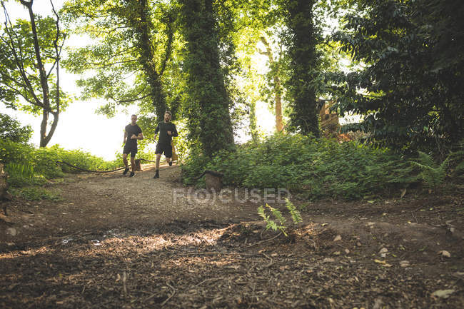 Двое мужчин бегают вместе в учебном лагере в солнечный день — стоковое фото