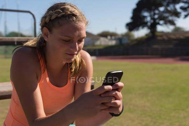 Sportlerin benutzte Handy am Sportplatz — Stockfoto