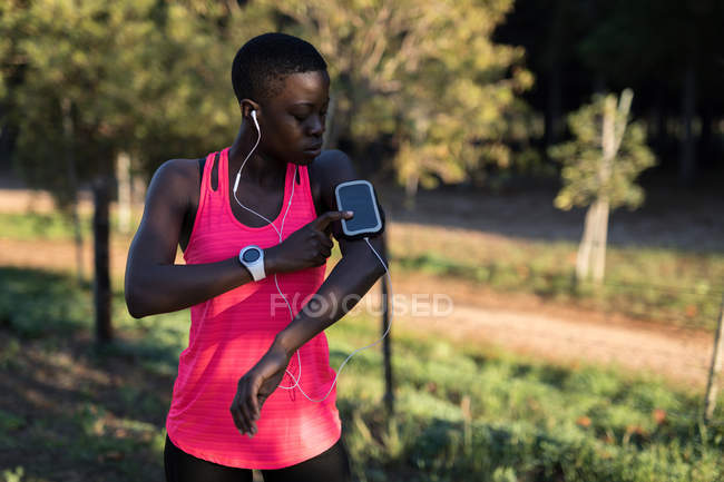 Спортсмен слушает музыку со смартфона mp3 плеера в лесу — стоковое фото