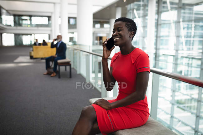Femme d'affaires souriante parlant au téléphone au bureau — Photo de stock