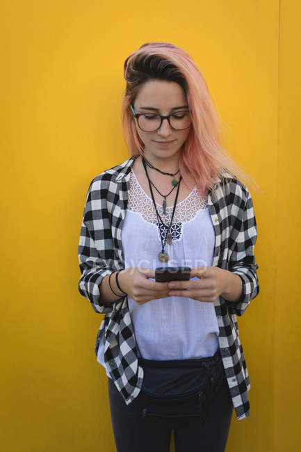 Jeune femme utilisant un téléphone portable sur le trottoir — Photo de stock