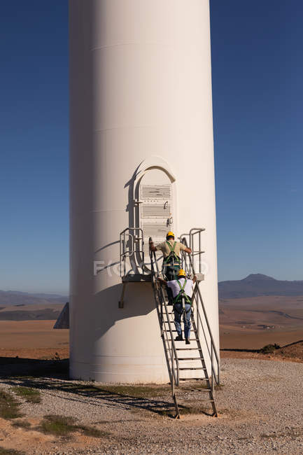 Інженери піднімаються по драбині на вітровому заводі на вітроелектростанції — стокове фото
