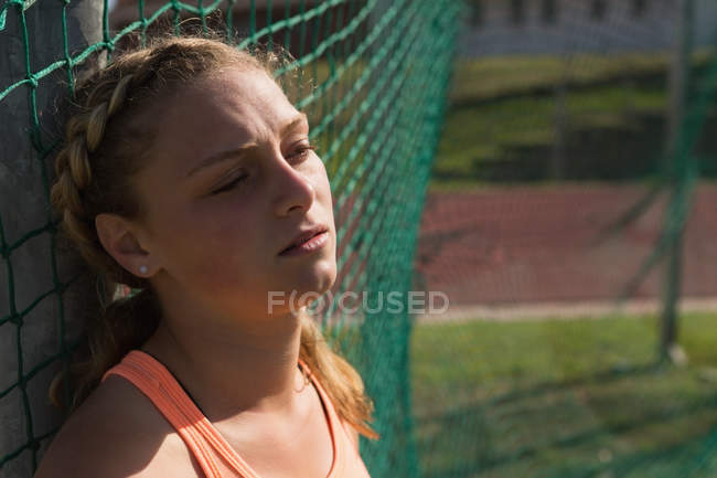 Atleta femenina reflexiva relajándose en el lugar de los deportes - foto de stock