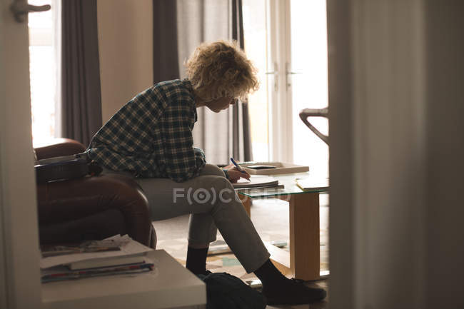 Jovem mulher escrevendo em um bloco de notas em casa — Fotografia de Stock