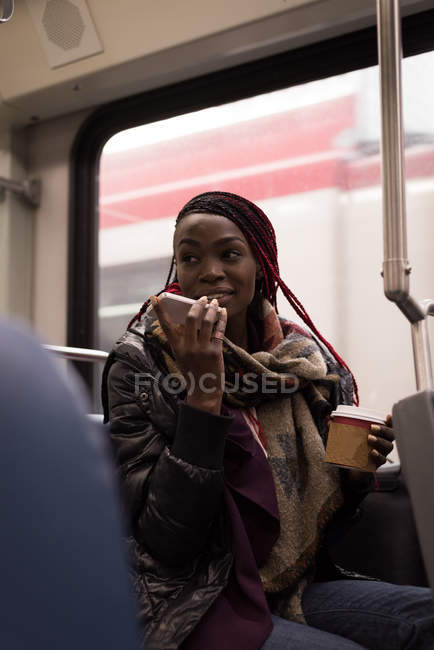 Mujer joven hablando por teléfono móvil mientras viaja en tren - foto de stock