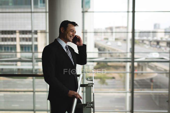 Усміхнений бізнесмен говорить на мобільному телефоні в офісі — стокове фото