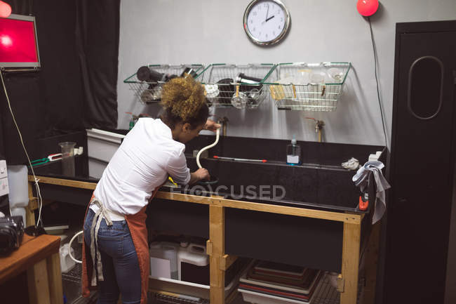 Fotógrafo feminino limpando uma tampa da lente da câmera no estúdio de foto — Fotografia de Stock