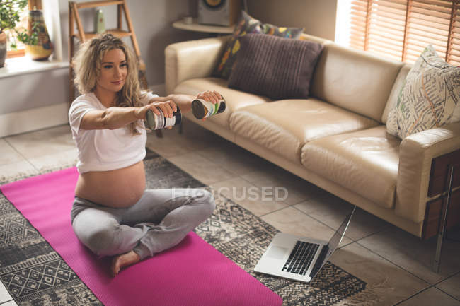 Donna incinta che si esercita in soggiorno a casa — Foto stock