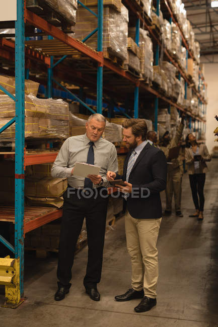 Personnel discutant sur presse-papiers dans l'entrepôt — Photo de stock