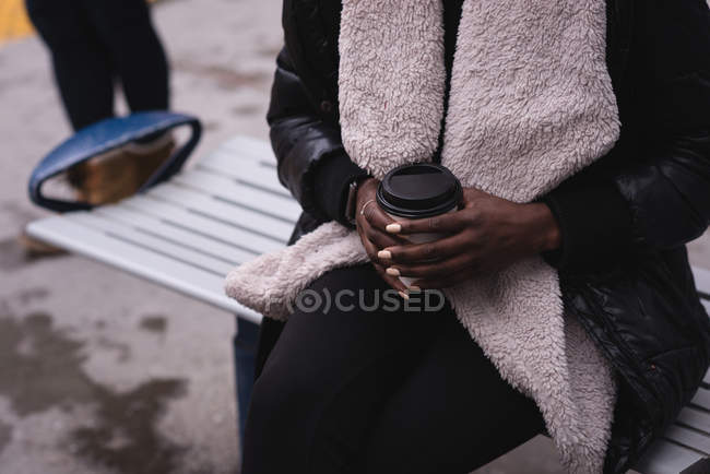 Seção média de mulher tomando café na estação ferroviária — Fotografia de Stock