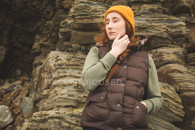 Задумчивая женщина-туристка прислонилась к скале — стоковое фото