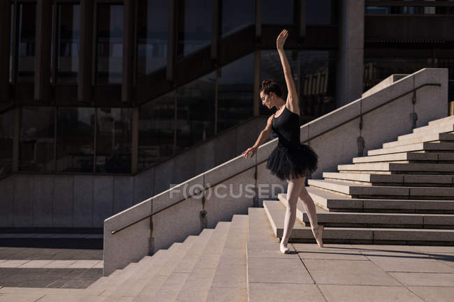 Woman performing ballet on the steps in the city — Stock Photo
