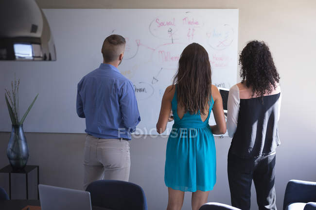 Führungskräfte diskutieren über Whiteboard im Büro — Stockfoto