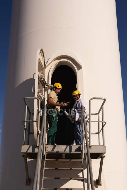 Engineers standing at the entrance of wind mill at a wind farm — Stock Photo