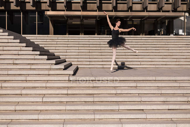 Woman performing ballet on the steps in the city — Stock Photo