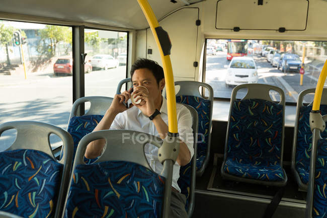 Man talking on mobile phone while having coffee in the bus — Stock Photo