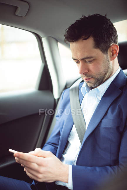 Homme d'affaires intelligent utilisant un téléphone portable dans une voiture — Photo de stock