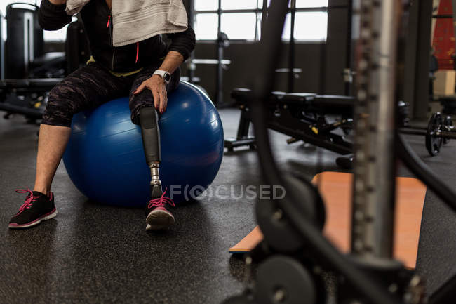 Inquiète femme handicapée assis sur le ballon d'exercice dans la salle de gym — Photo de stock