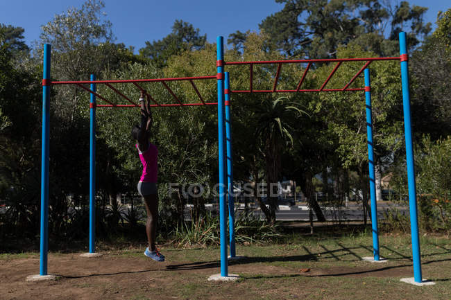 Deportista femenina determinada ejercitándose en barras de mono - foto de stock