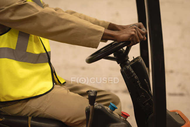 Mid section of male driving forklift in warehouse — Stock Photo
