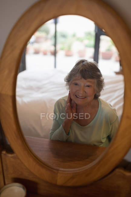 Senior mulher olhando para si mesma no espelho no quarto — Fotografia de Stock