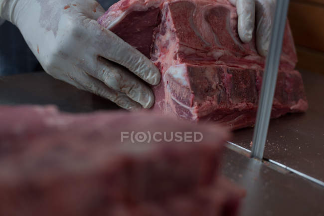 Крупный план мясника, держащего мясо в мясной лавке — стоковое фото