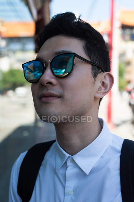 Молодий чоловік в сонцезахисних окулярах стоїть на вулиці міста — стокове фото