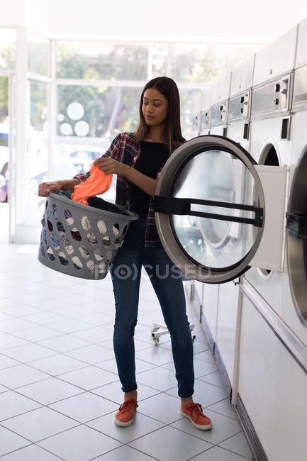 Jeune femme faisant la lessive dans la laverie automatique — Photo de stock