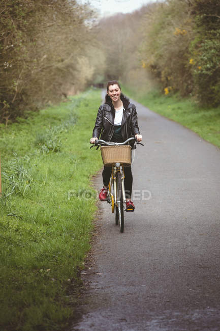 Portrait of beautiful woman riding bicycle at country road — Stock Photo