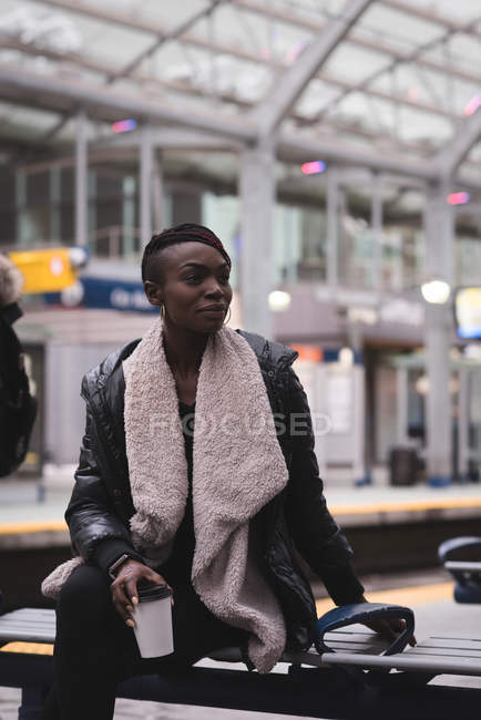Молода жінка має каву на вокзалі — стокове фото