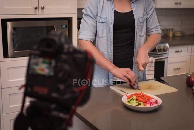 Mujer preparando ensalada en la cocina en casa - foto de stock