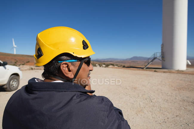 Інженер стоїть біля вітрового млина на вітроелектростанції — стокове фото