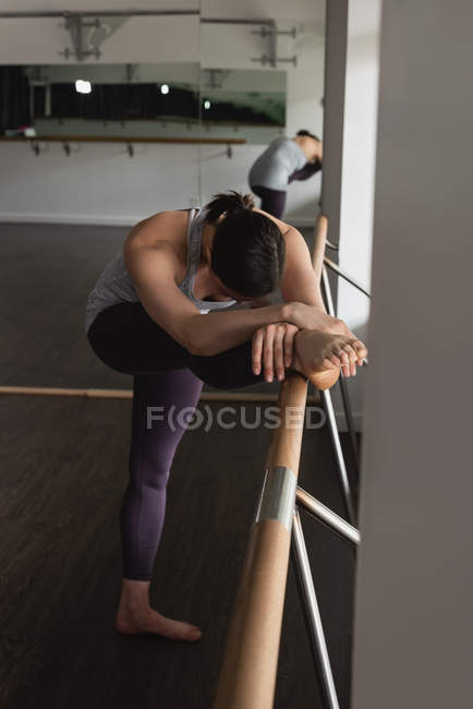 Jovem praticando perna esticando-se no barro no ginásio — Fotografia de Stock