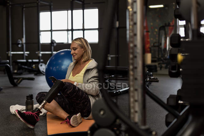 Behinderte ältere Frau benutzt Handy im Fitnessstudio — Stockfoto